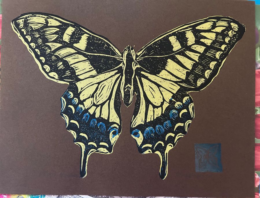 Hand-carved block print of a yellow swallowtail butterfly on brown paper